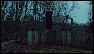 a creepy picture of a gate in the woods