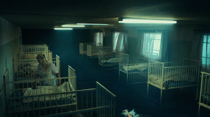 a woman in a white dress standing in a room with bunk beds