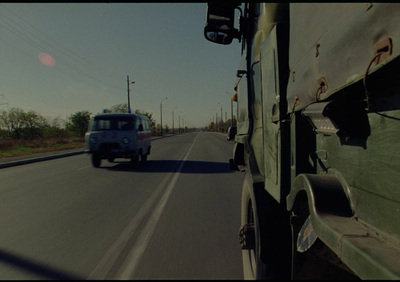 a blue truck driving down a road next to a forest