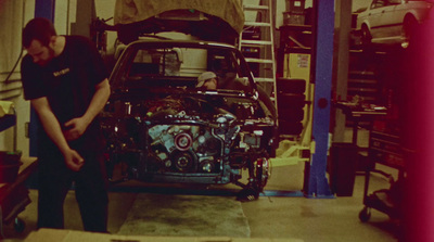 two men working on a car in a garage