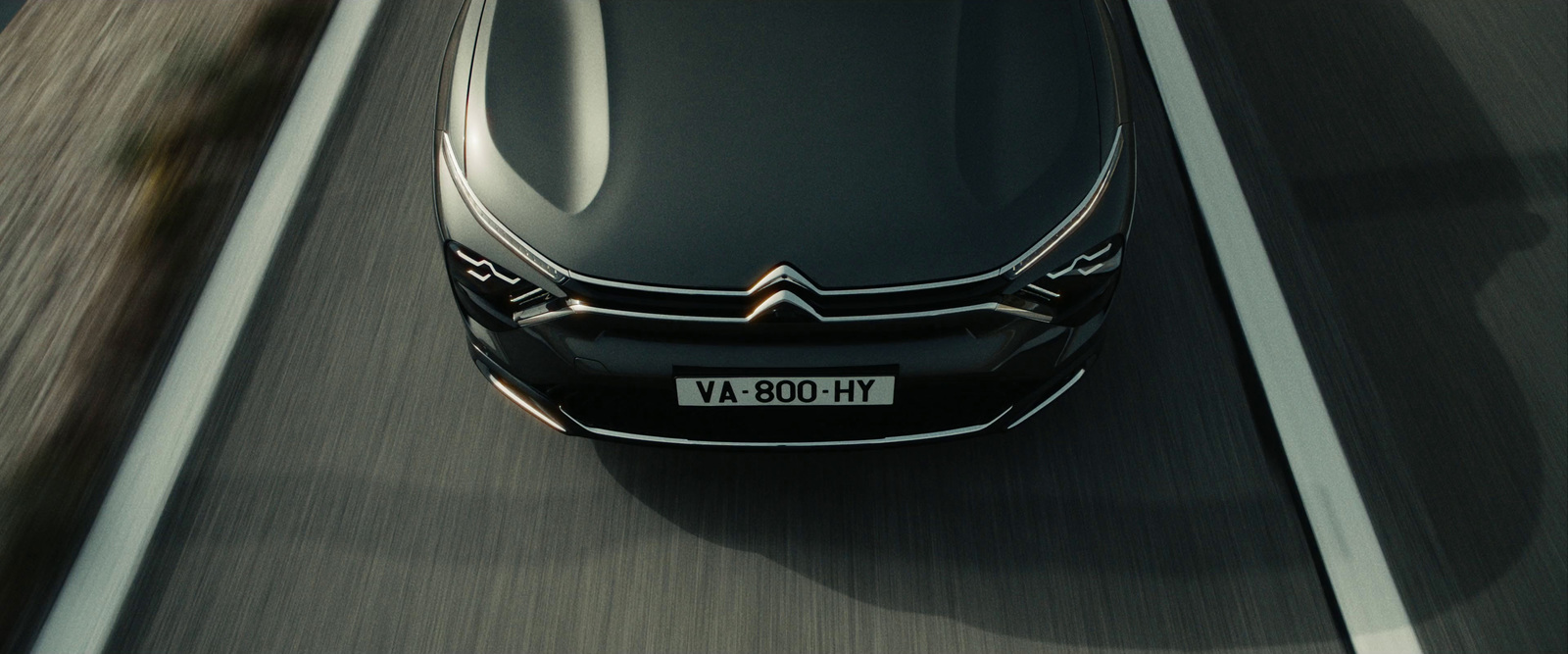 a black car driving down a highway next to a forest