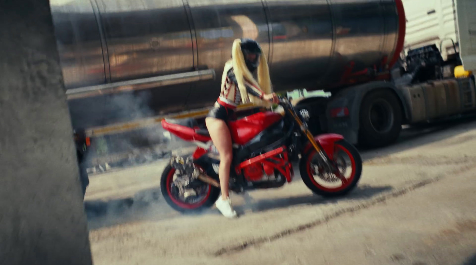 a woman riding a red motorcycle down a street