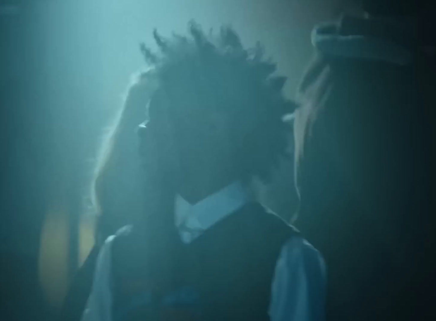 a man with dreadlocks standing in a dark room