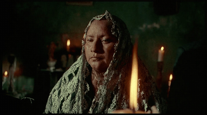 a woman with a veil on her head sitting in front of candles