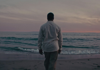 a man standing on top of a beach next to the ocean