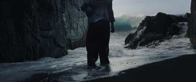 a man standing on a beach next to a cliff