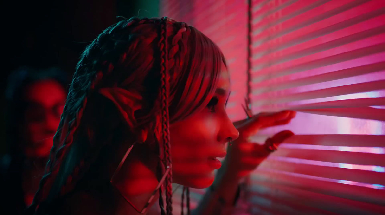 a woman standing next to a window covered in red light