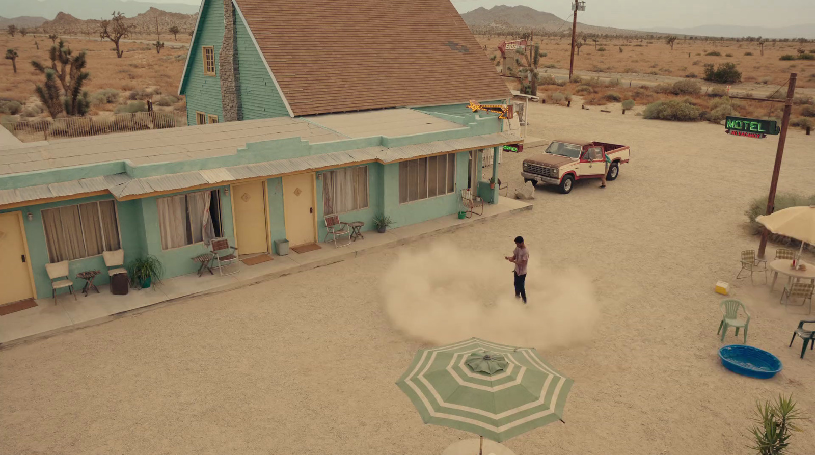 a person standing in front of a motel with an umbrella