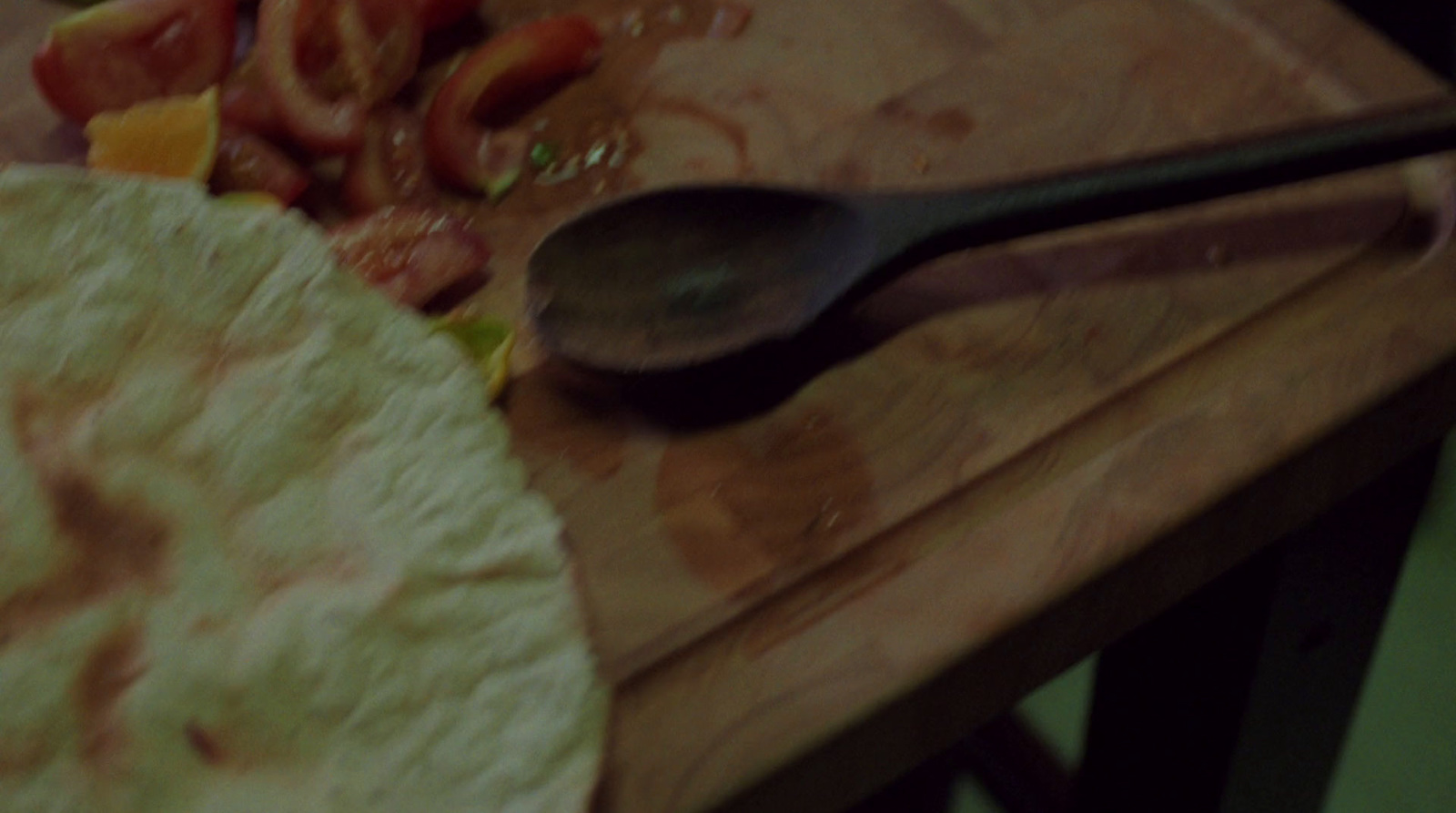 a wooden cutting board topped with a tortilla and a spoon