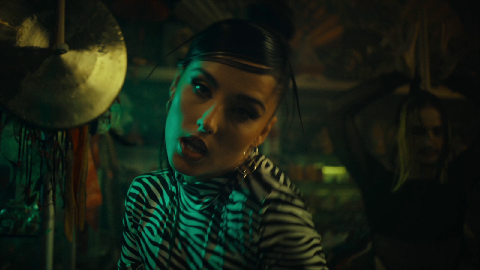 a woman in a zebra print shirt standing in front of a drum set