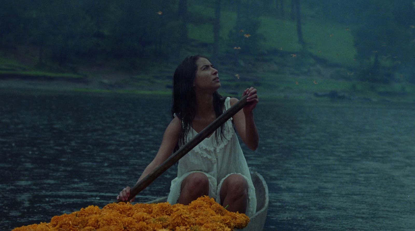 a woman in a white dress sitting on a boat filled with flowers