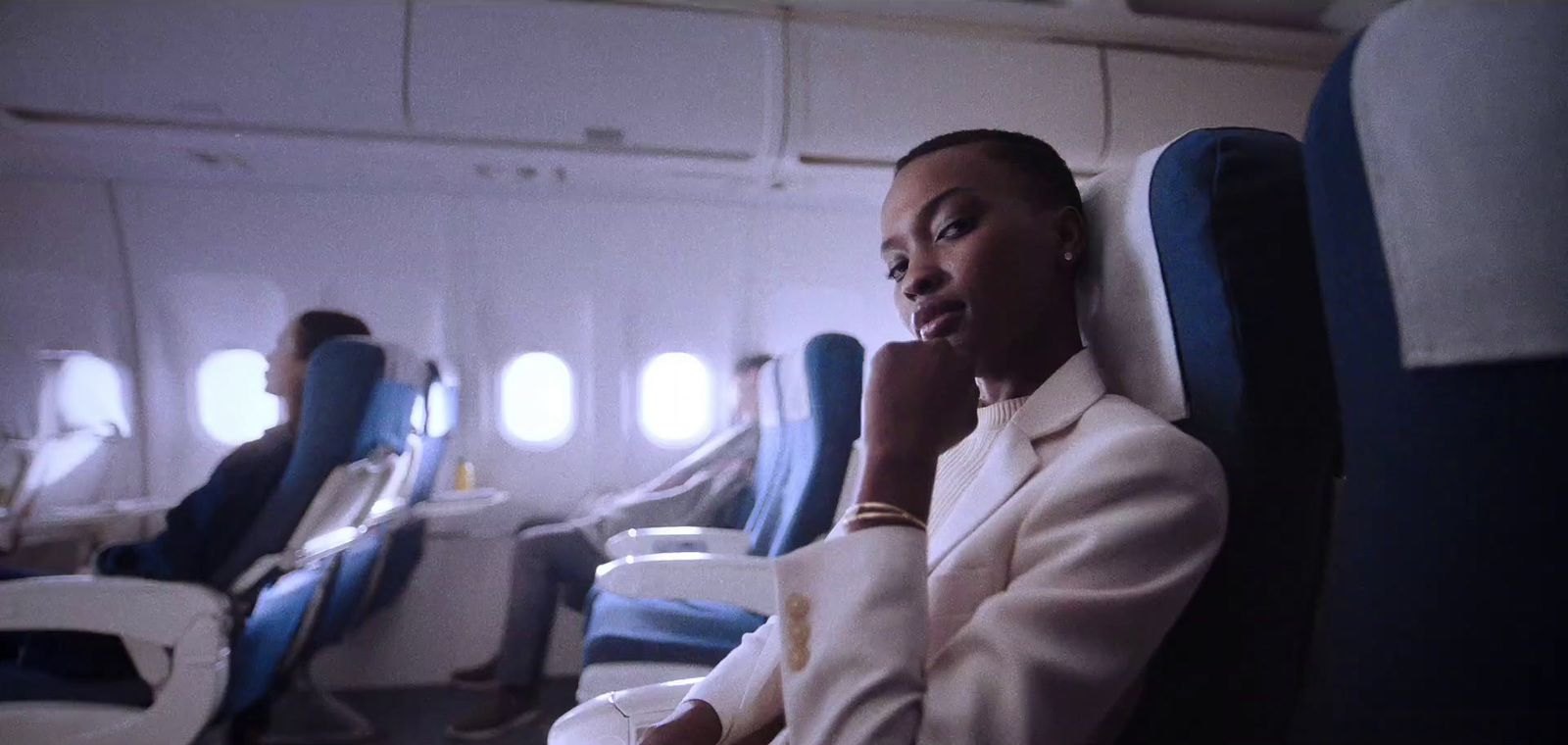 a woman in a white suit sitting on an airplane