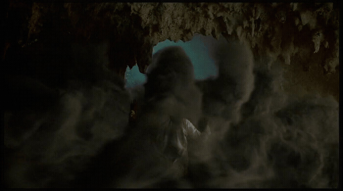 a person standing in a cave with smoke coming out of it