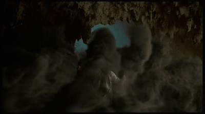 a person standing in a cave with smoke coming out of it