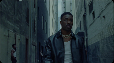 a man in a leather jacket walking down a street