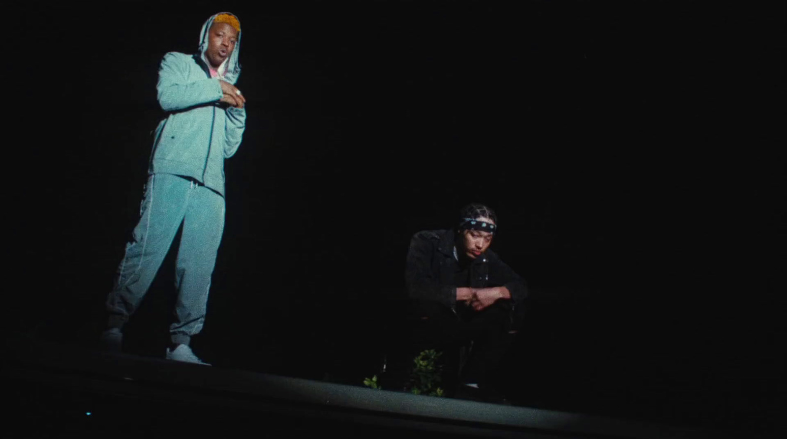 two men standing on top of a roof in the dark