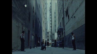 a group of people walking down a street next to tall buildings