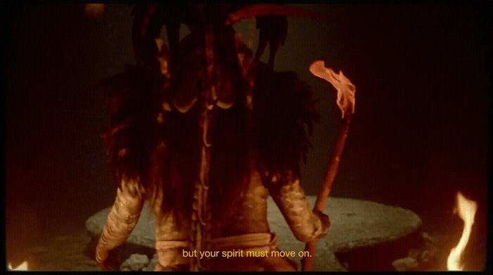 a man with dreadlocks standing in front of a fire