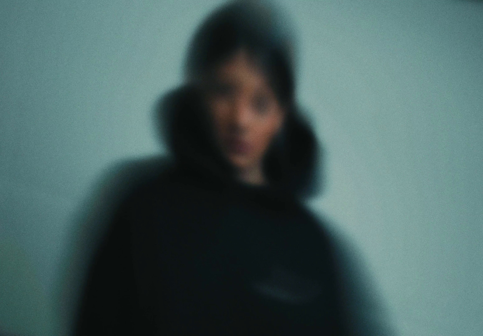 a blurry photo of a person in a black hoodie