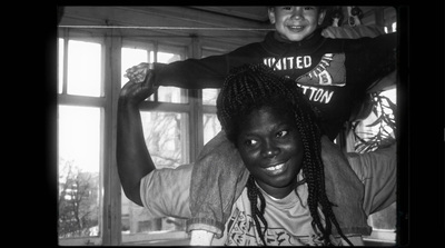 a black and white photo of a woman holding a child on her shoulders