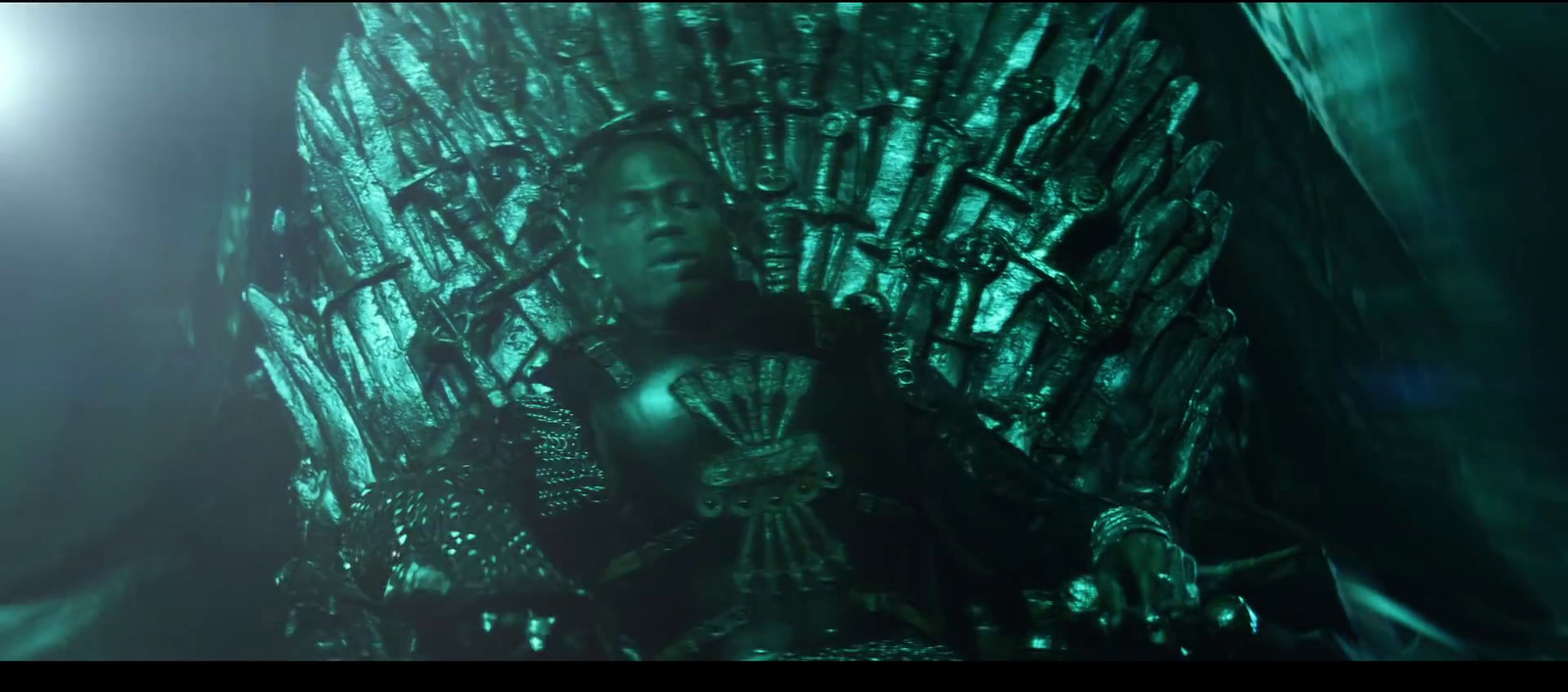 a man sitting on top of a green iron throne