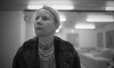 a woman with a pearl necklace standing in a hallway