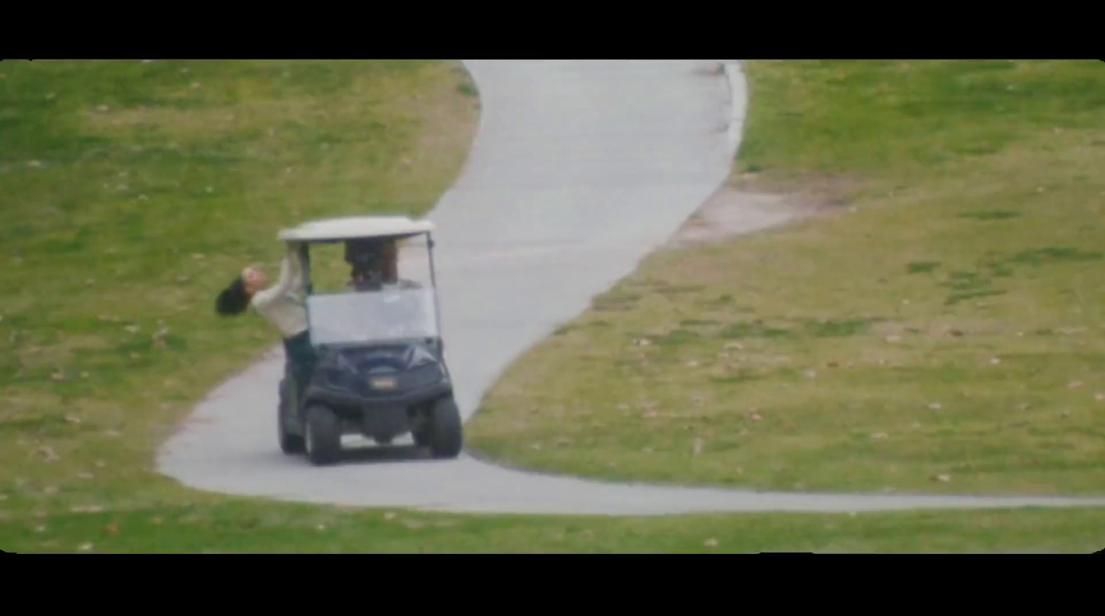 a man driving a golf cart down a winding road