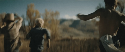 a group of people running through a dry grass field