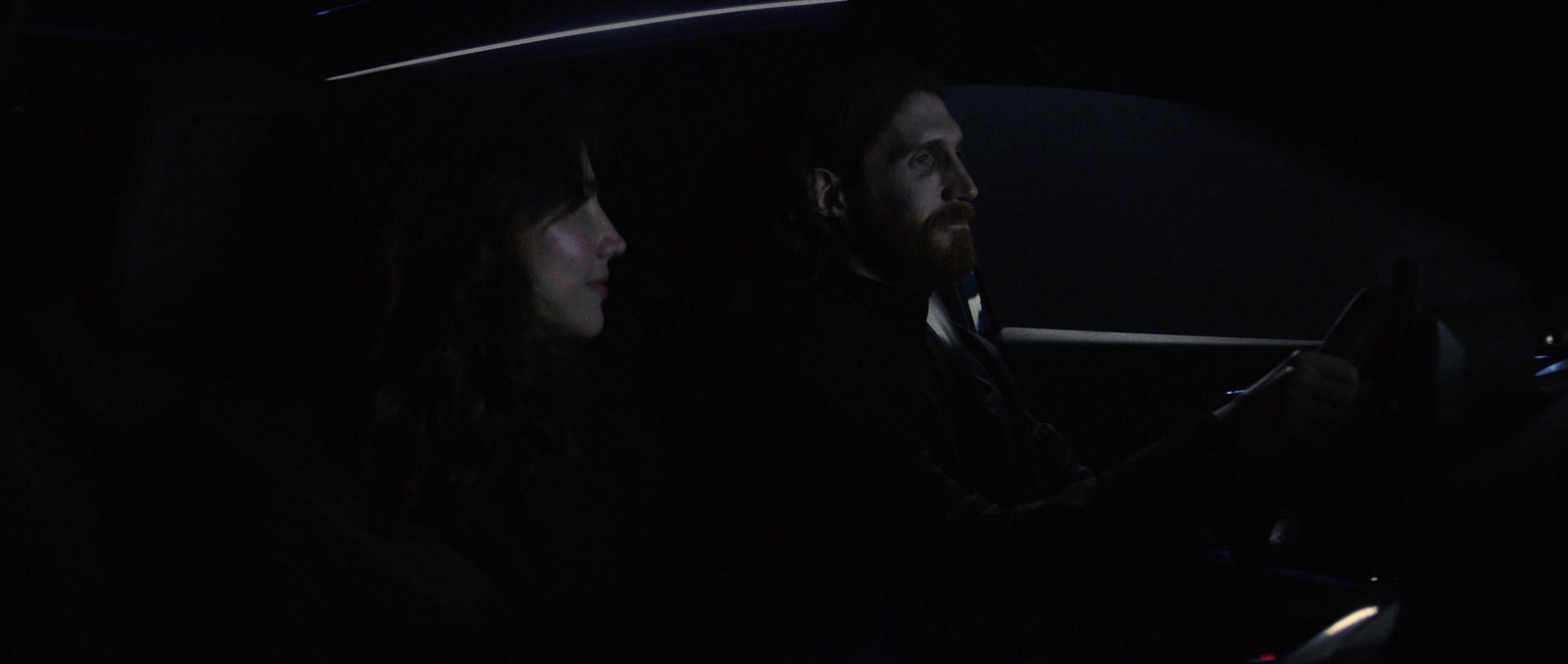 a man and a woman sitting in a car at night