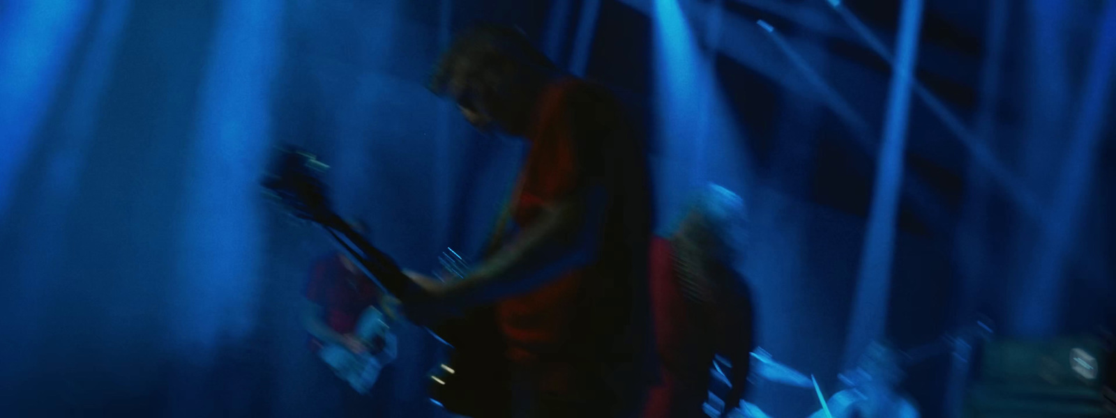 a man playing a guitar in front of blue lights