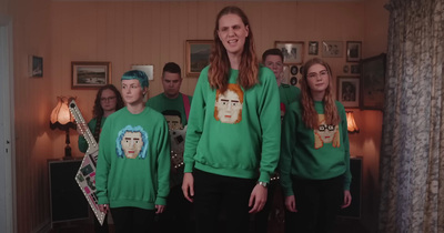 a group of people in green sweaters standing in a room