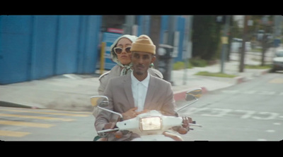 a man and woman riding a motorcycle down a street