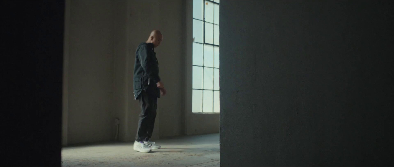 a man standing in an empty room looking out the window