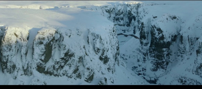 a snowy mountain side with a large cliff