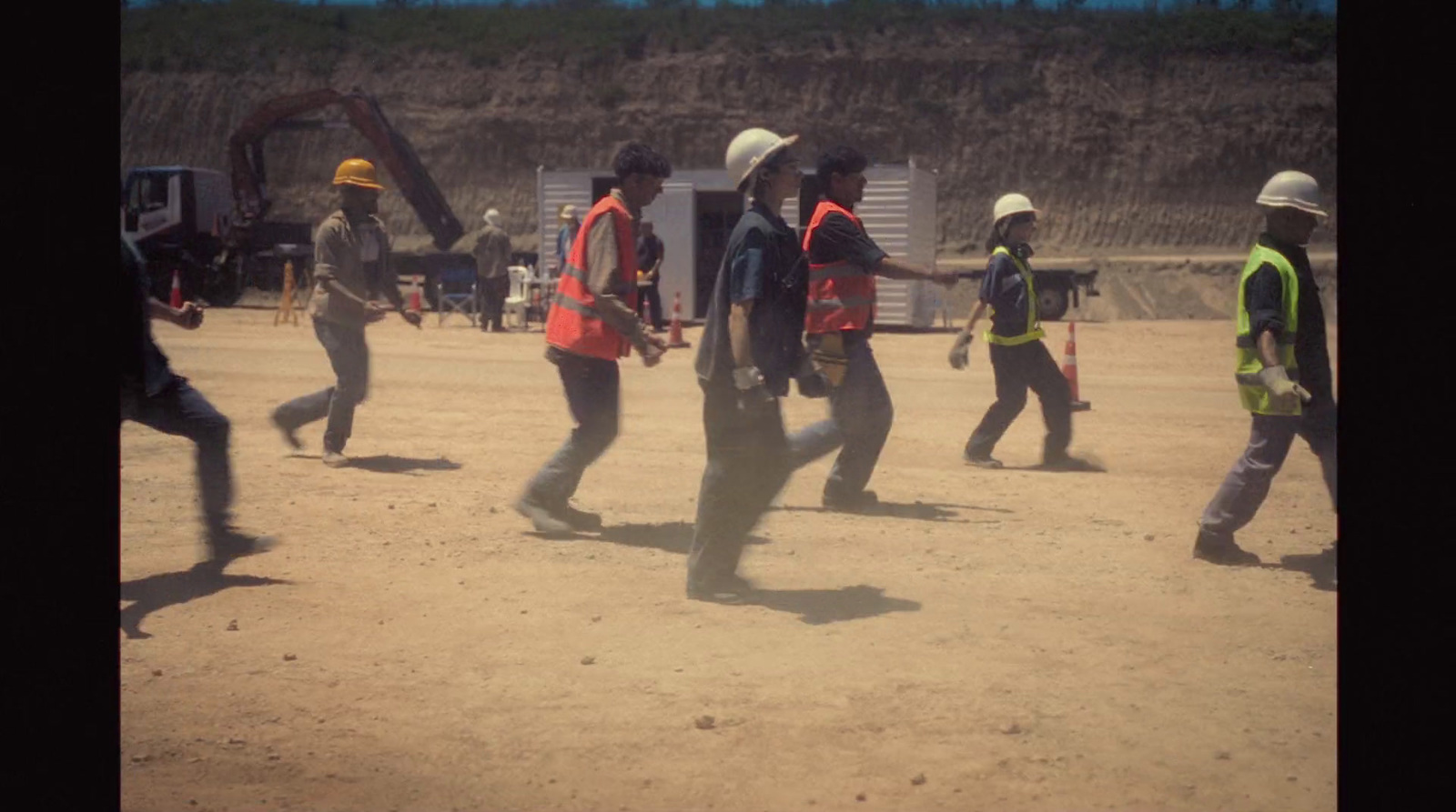 a group of people walking across a dirt field