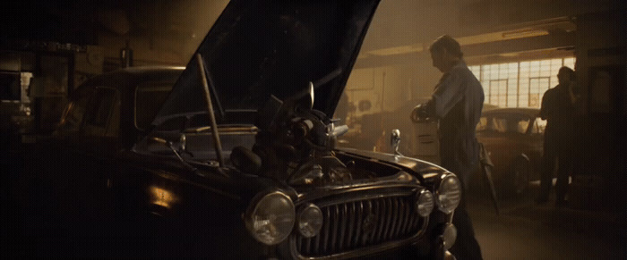 a man standing next to a car in a garage