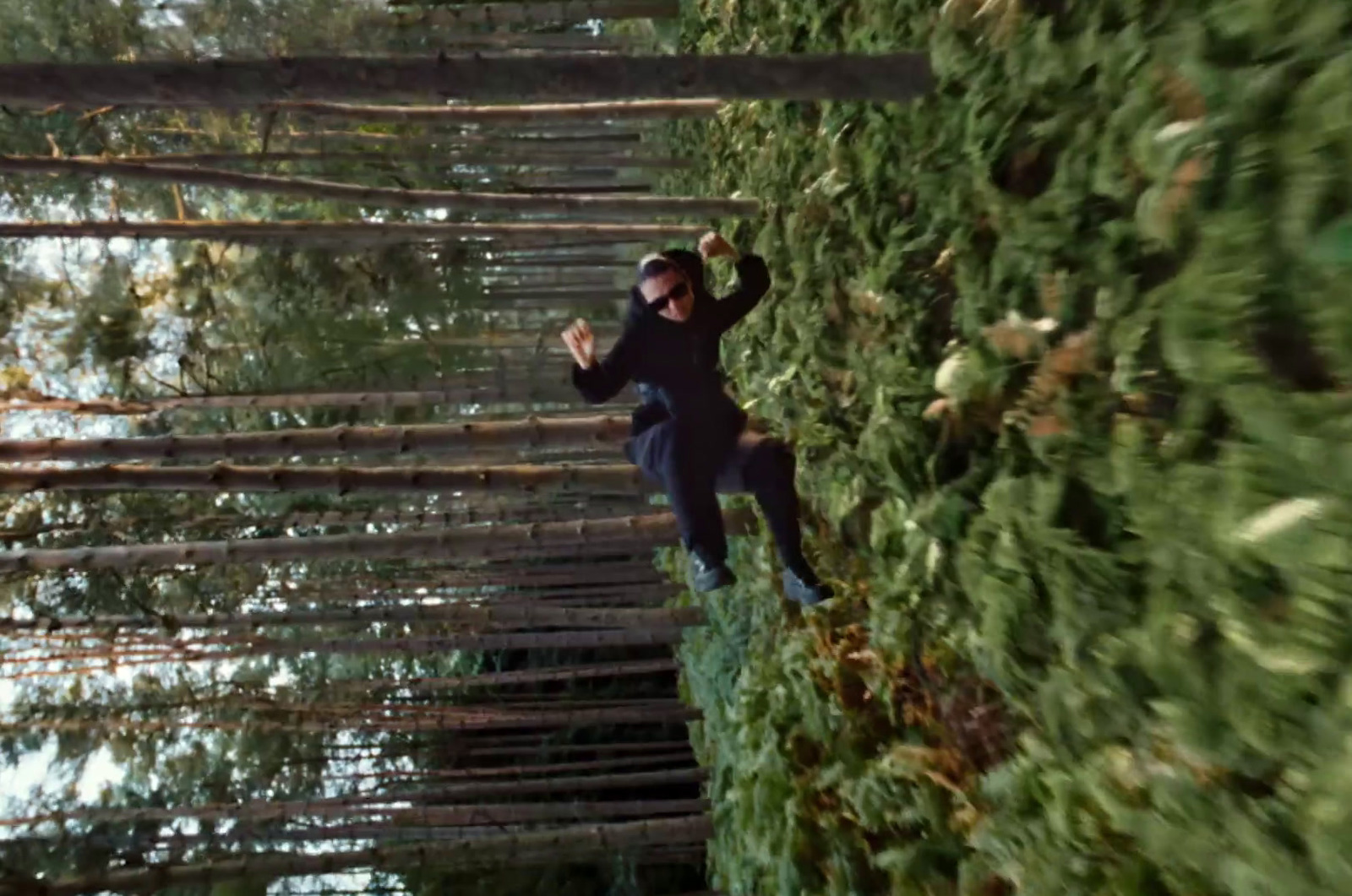 a man walking across a bridge made of trees