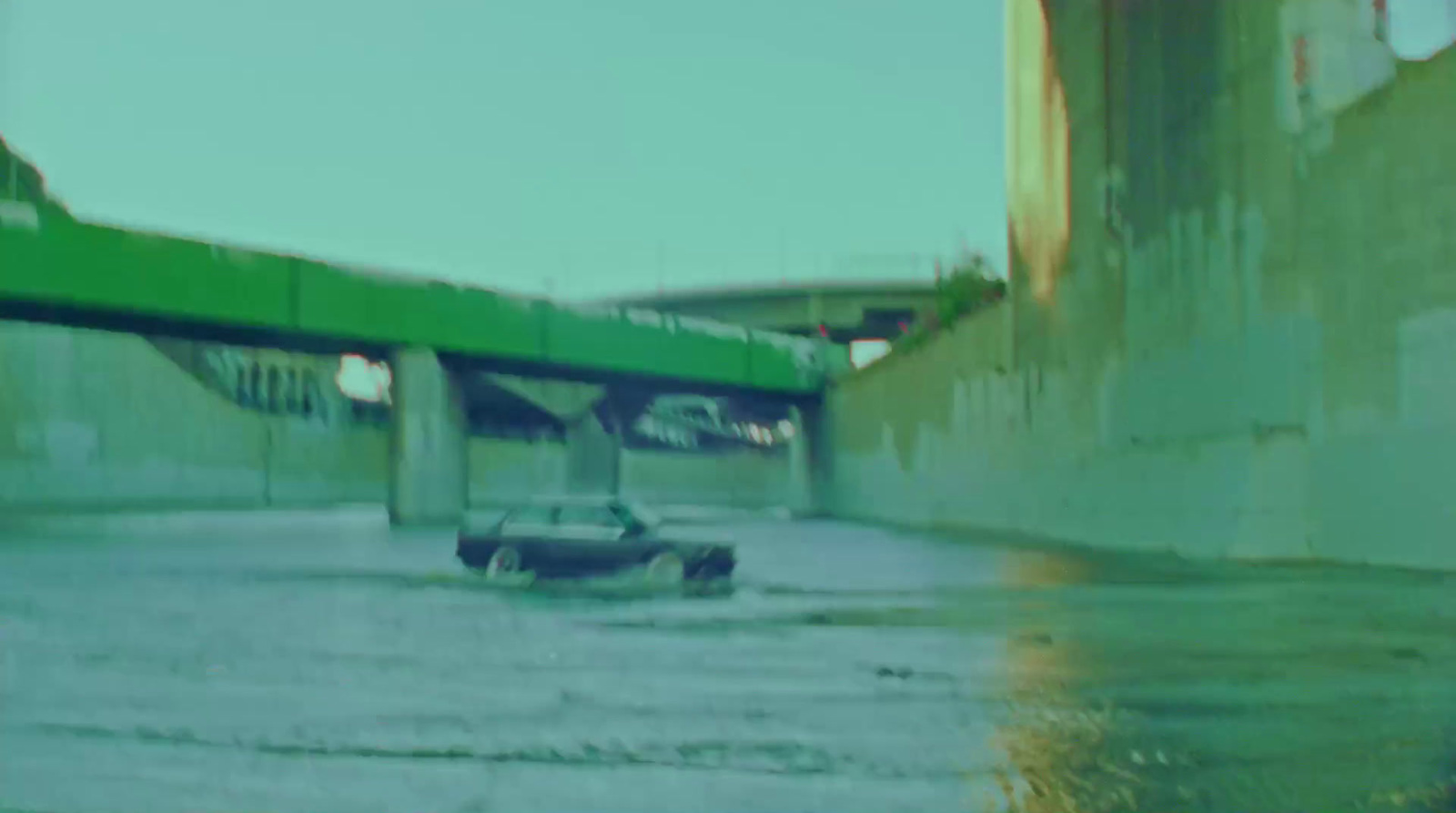 a car driving through a flooded street under a bridge