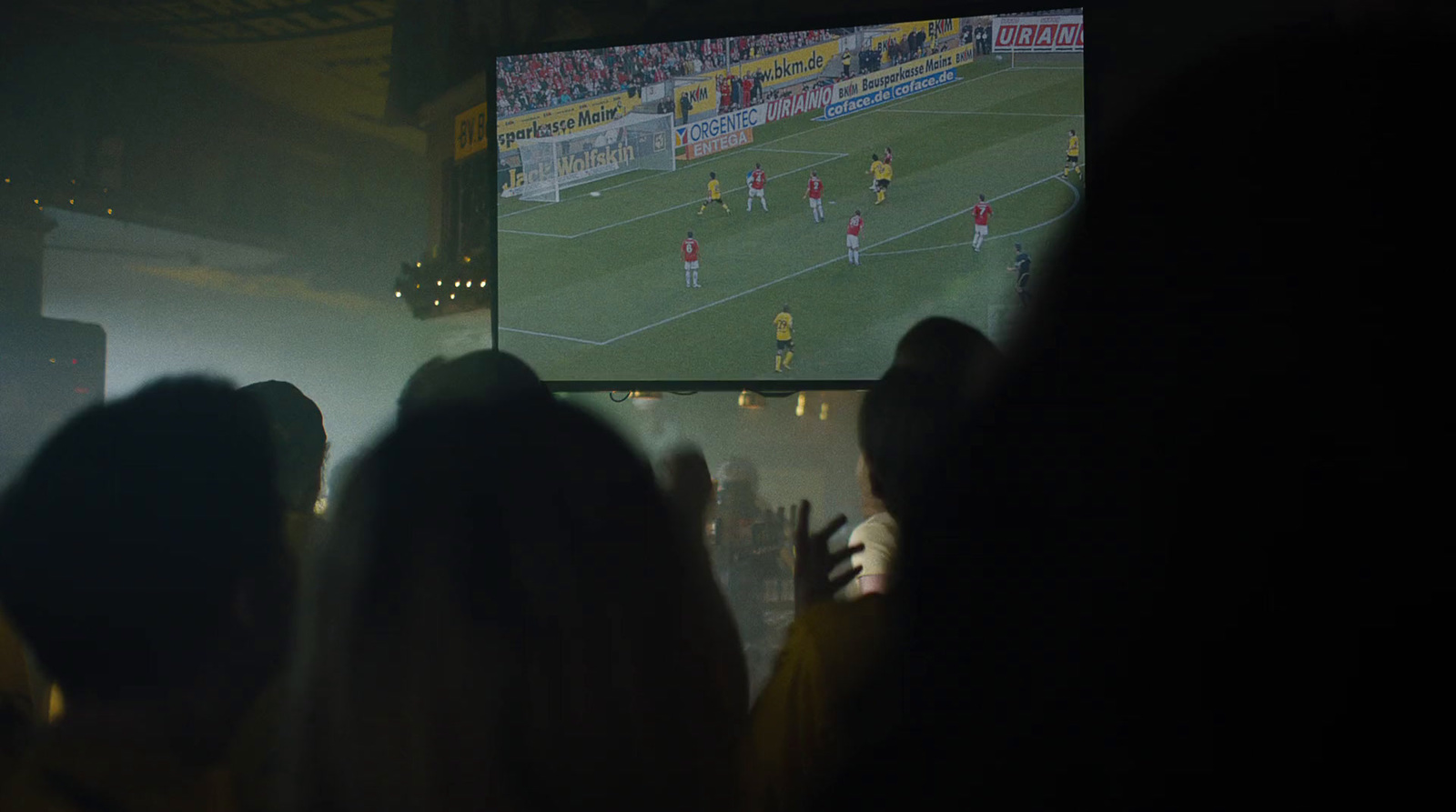 a group of people watching a soccer game on a large screen