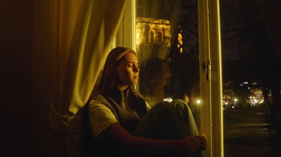 a woman sitting in front of a window at night