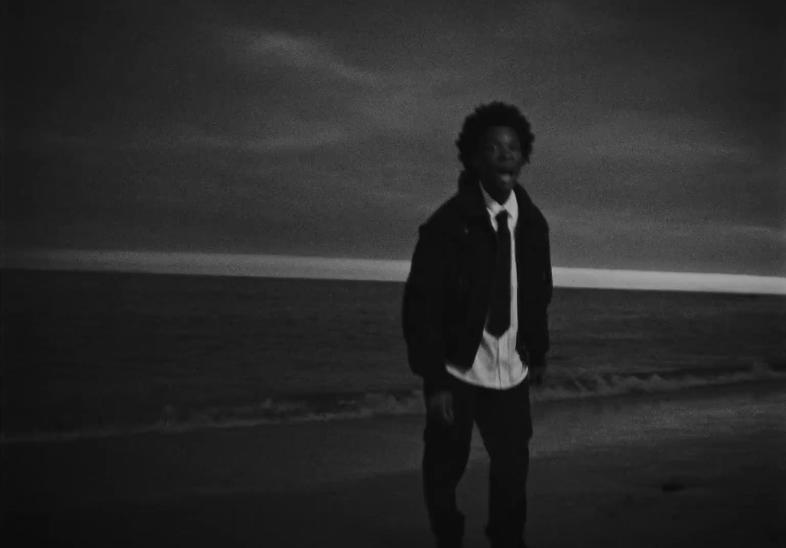 a man standing on top of a beach next to the ocean