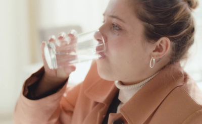 a woman drinking water out of a glass