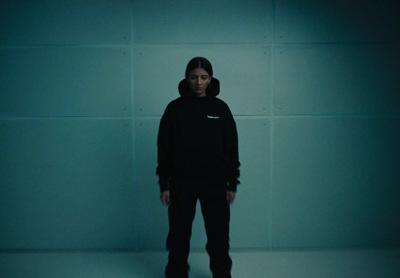 a man in a black hoodie standing in a dark room