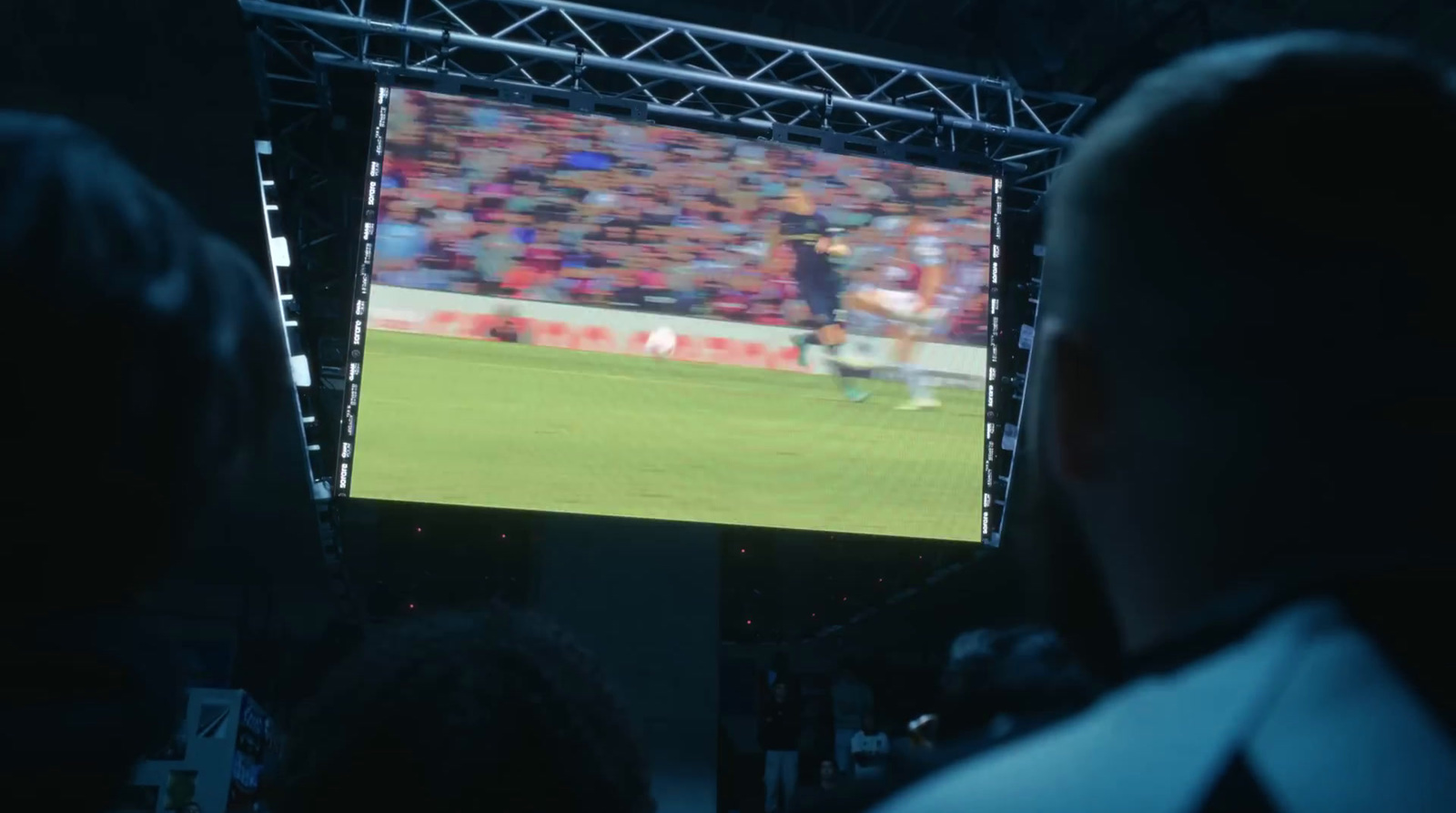 a man is watching a soccer game on a big screen