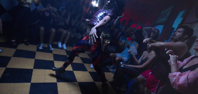 a man is dancing on a checkered floor in front of a group of people