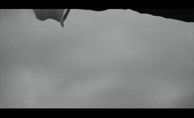 a black and white photo of a kite flying in the sky