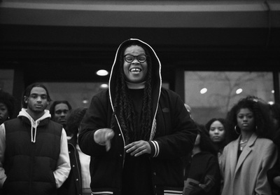 a man with dreadlocks standing in front of a group of people