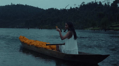 a woman sitting in a boat filled with orange flowers