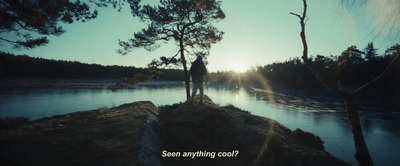 a man standing on top of a rock next to a lake