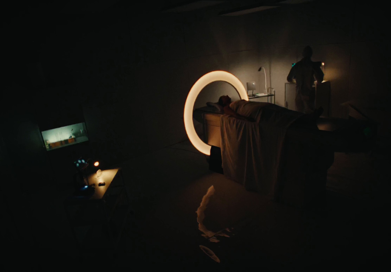 a man standing in a dark room next to a bed